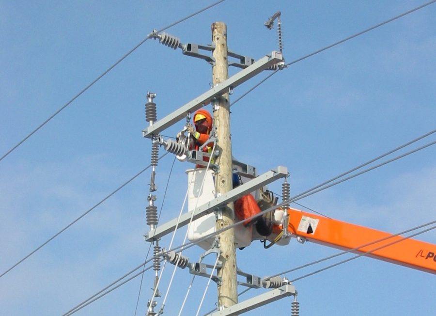 Man in orange working on the electrical lines
