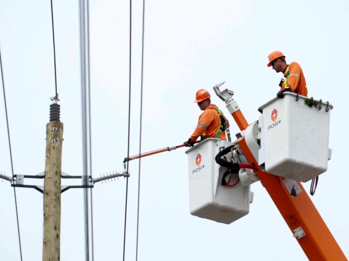 two men in a bucket working on power lines